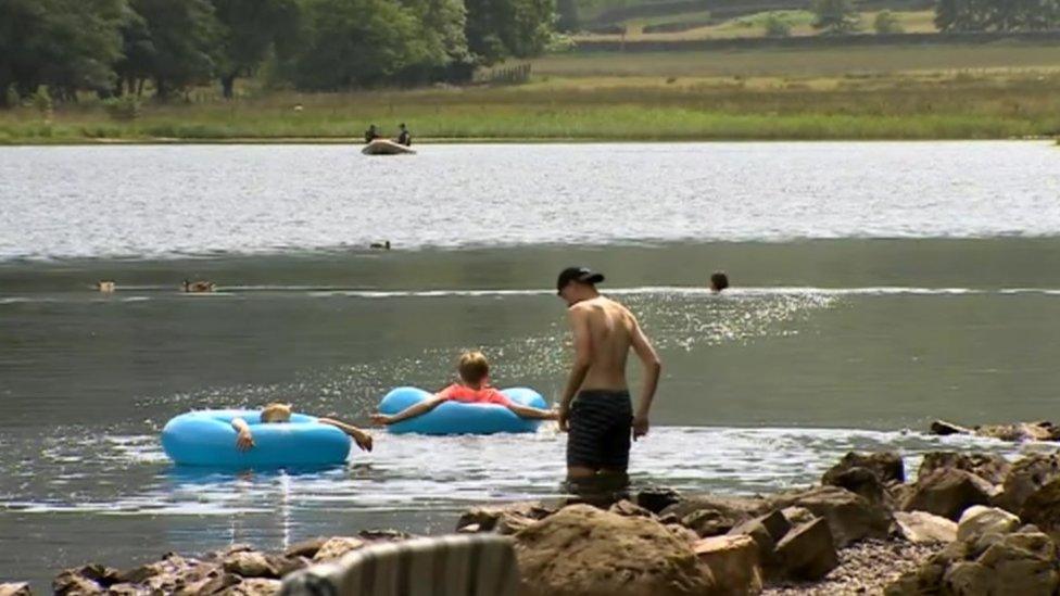 Families at the lake with a search boat in the background