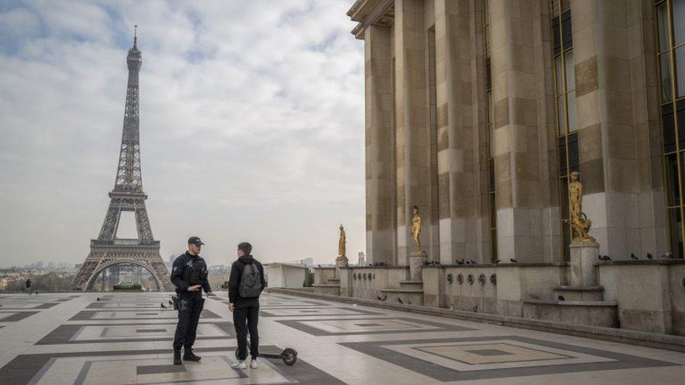 Police officers question a scooter rider travelling near the Eiffel Tower hours after a government enforced quarantine on March 17, 2020 in Paris, France