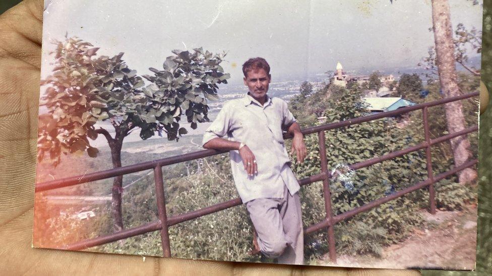 Om Prakash's son holds up a photo of his father from the family album