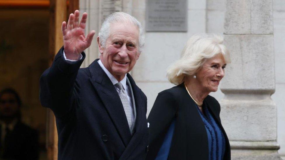 King Charles smiles and waves as he leaves hospital accompanied by a smiling Camilla