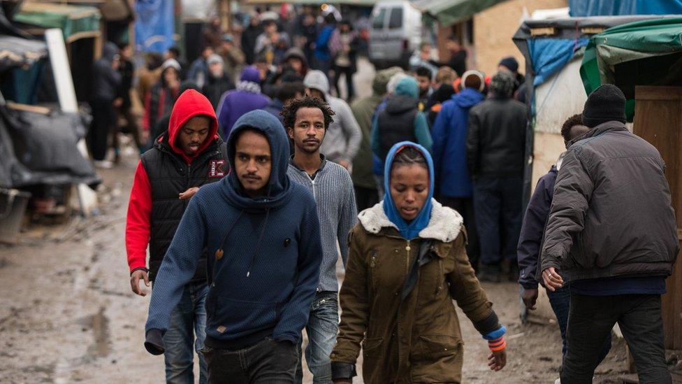 Migrants walk through the camp known as "The Jungle" in Calais