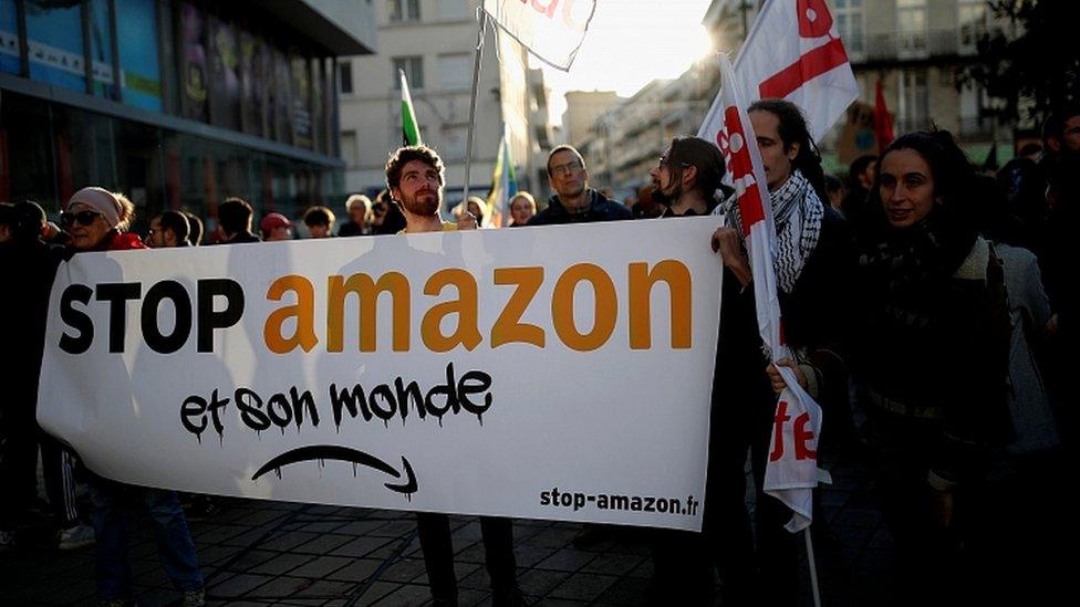 Activists hold a banner that reads: "Stop Amazon and its world" as they demonstrate in Nantes, France, November 29, 2019