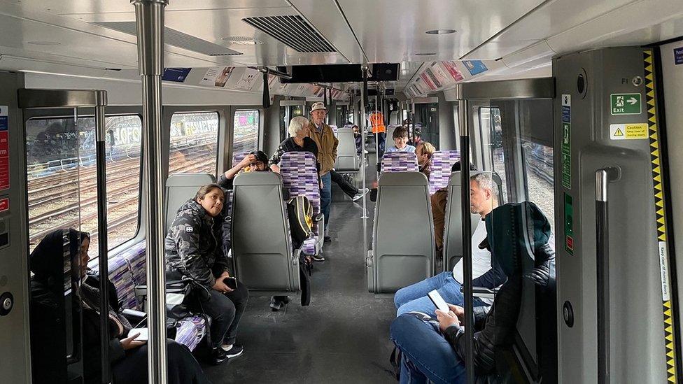 Members of the public on a Elizabeth Line train at standstill outside Royal Oak station in London