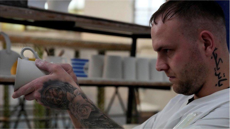 A worker checks the handle for chinaware at a factory in Stoke-on-Trent