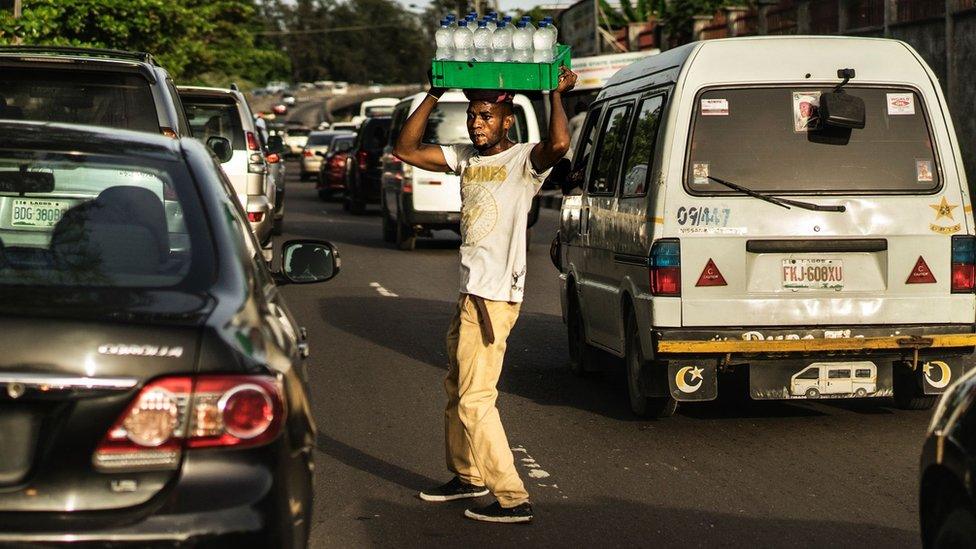 Male sells water in the middle of a busy road in Lagos