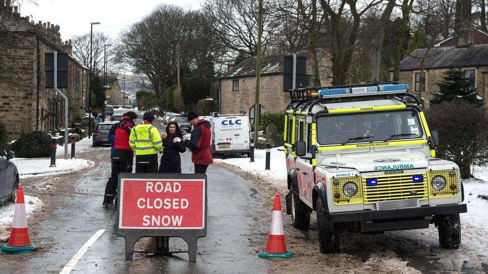 A mountain rescue crew receive hot drinks in a street