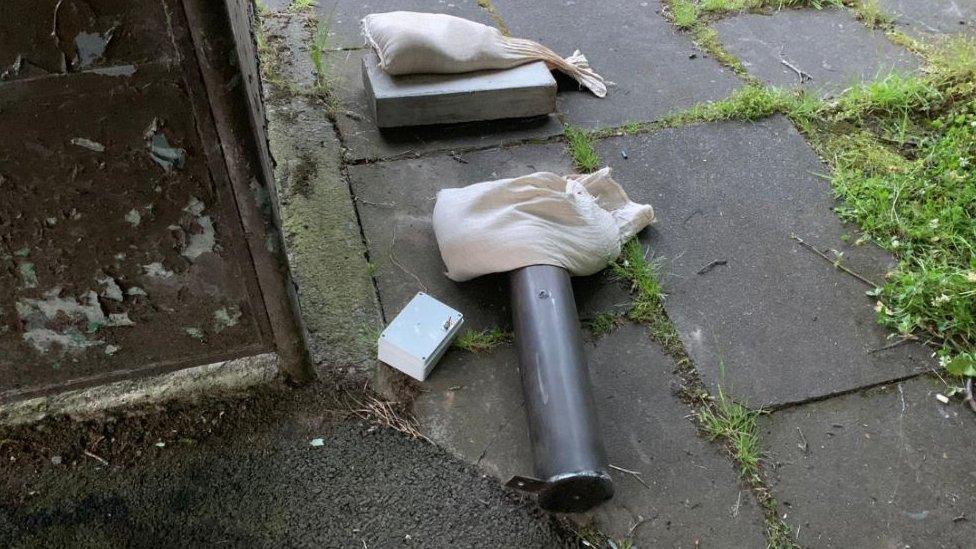 An explosive device lies on the ground nest to a public bus stop.