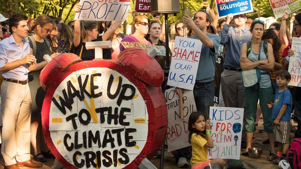 sign made to look like an alarm clock, that says "Wake up to climate change"