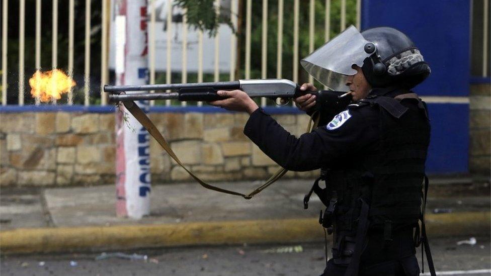 A riot police officer fires a weapon during clashes with students taking part in a protest in Managua on May 28, 2018