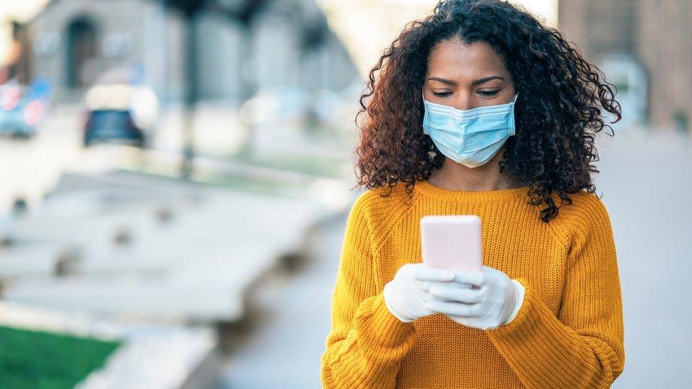 woman-with-gloves-and-mask-holding-phone.