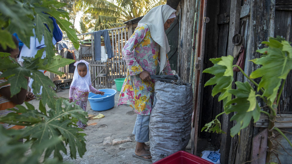 A young girl prepares a bag of coal to be used for cooking in preparation for Eid food in Fort Dauphin, Madagascar