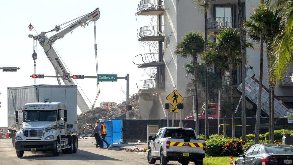 Workers clean the area of the partially collapsed Champlain Towers South condominium building in Surfside, Florida, 4 July 2021