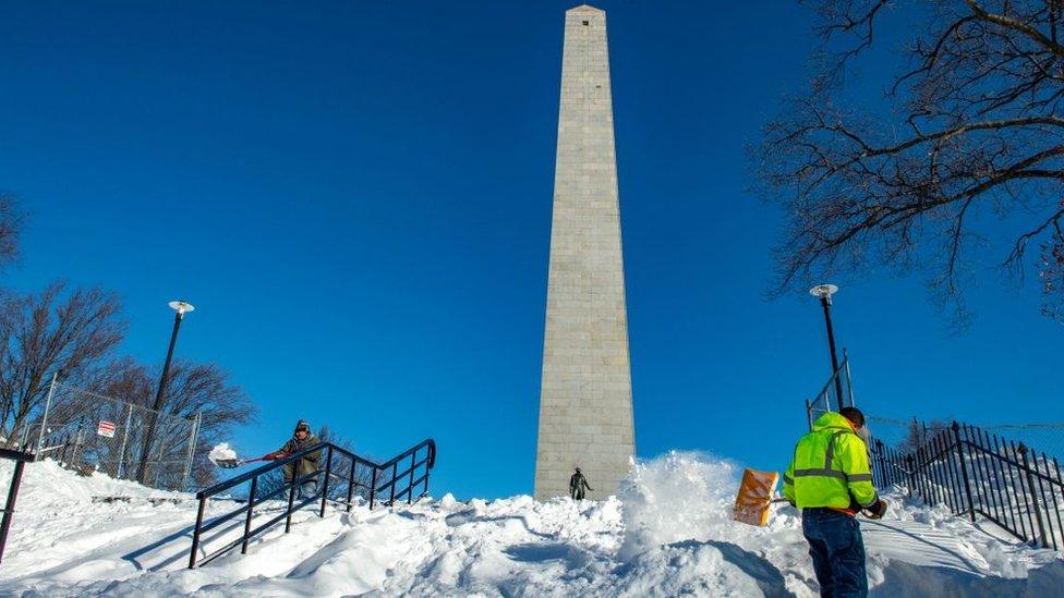 A worker clears snow away from the base of the Bunker Hill memorial