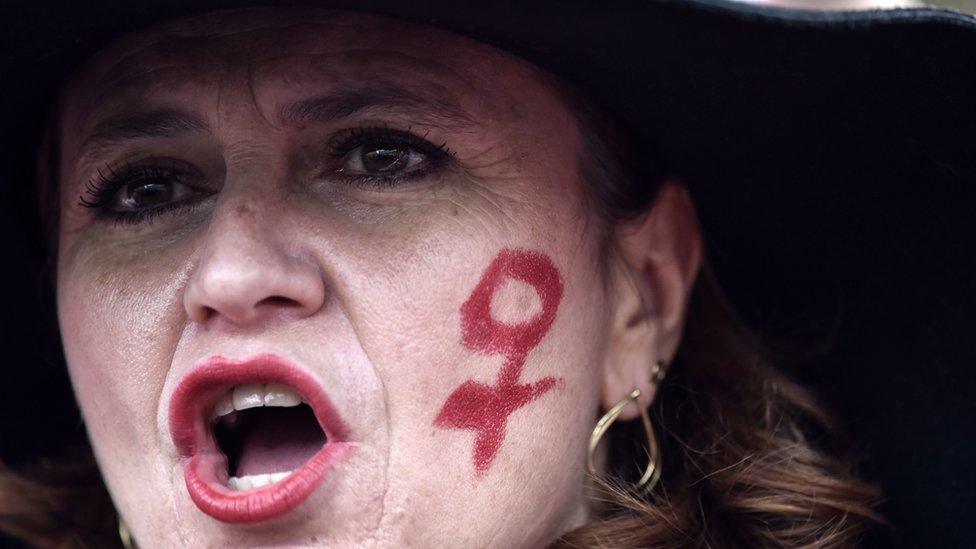 A woman with the female gender symbol on her cheek takes part in a march as part of the International Day for the Elimination of Violence against Women, on November 24, 2018 in Rome