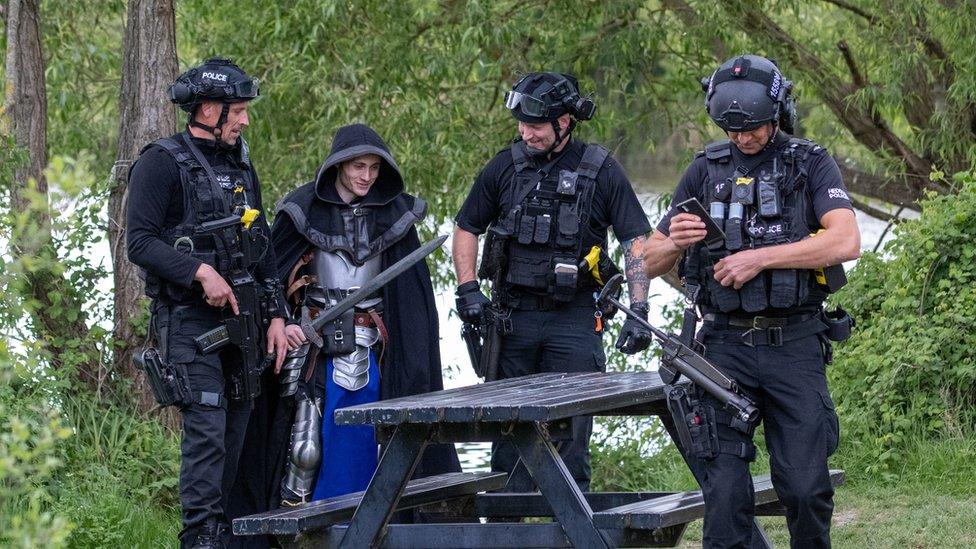 Armed police posing for pictures with a knight