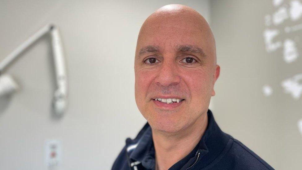 Dr Jason Lester in a clinical consulting room. He is wearing a navy top.