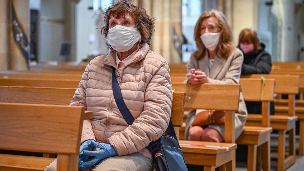 Three women with masks on praying