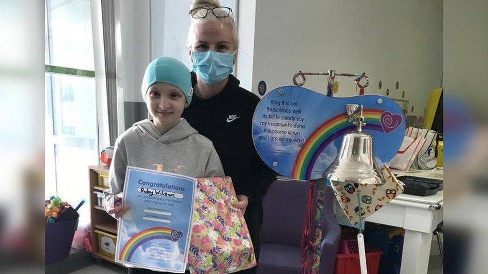 Ruby and her mum with the bell and a certificate