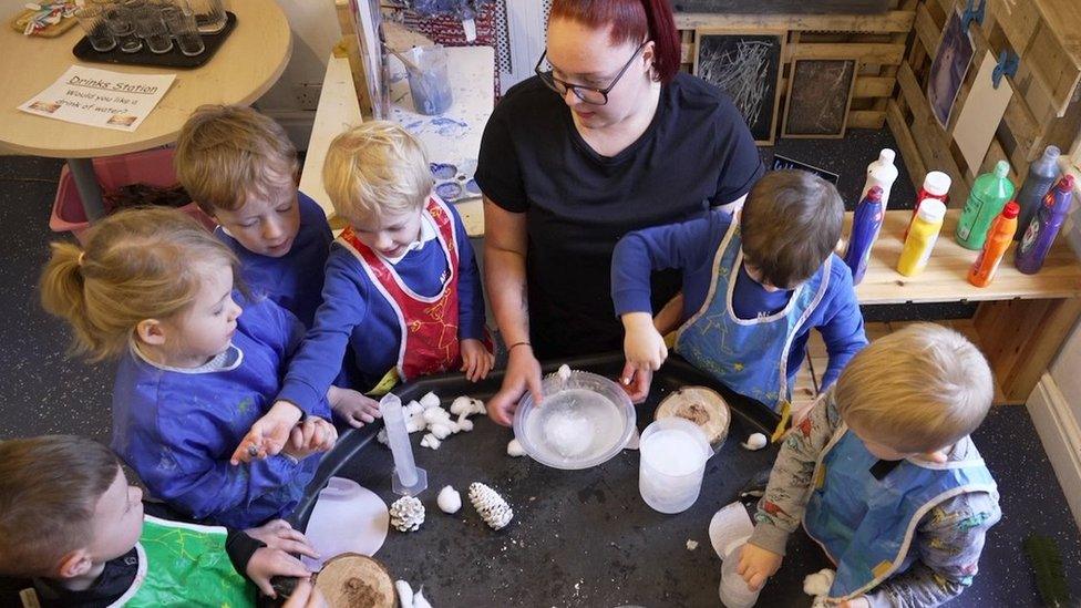 Children and a teacher doing craft activities around a table