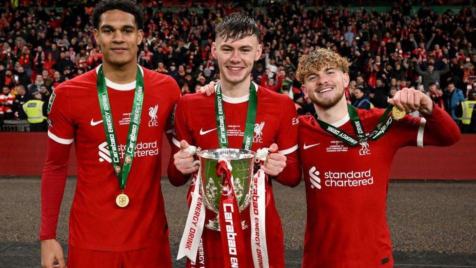 Liverpool's Conor Bradley pictured with the League Cup trophy alongside Jarell Quansah and Harvey Elliott.