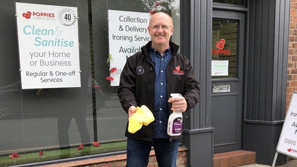 The boss of cleaning firm Poppies, Chris Wootton holding a spray bottle and sponge