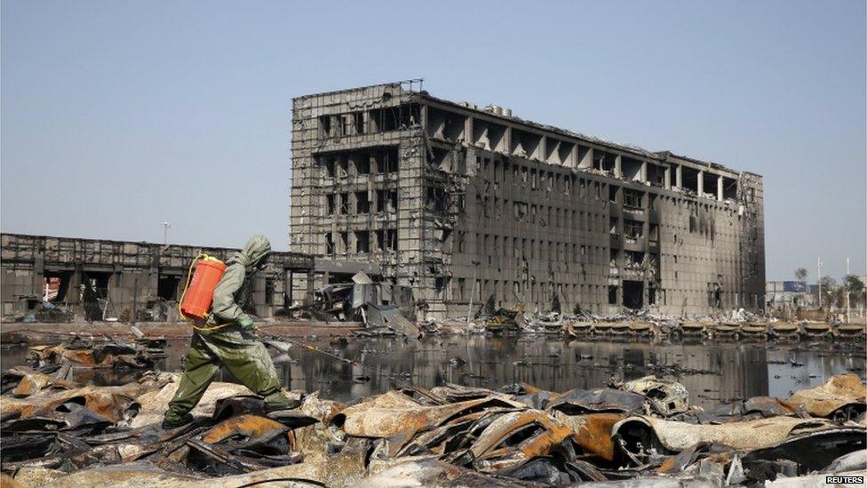 A People's Liberation Army (PLA) soldier of the anti-chemical warfare corps in protection suit sprays liquid on the debris at the site of last week's blasts in Binhai new district of Tianjin, China, 21 August 2015