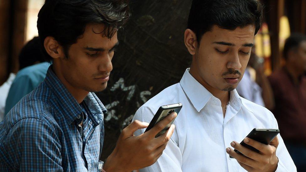 Indian pedestrians check their cellphones