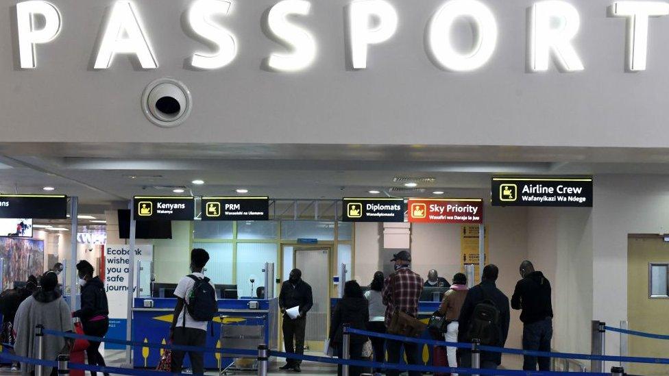 Passengers, wearing protective face masks, queue at passport control desks at the Jomo Kenyatta international airport in Nairobi, on August 1, 2020