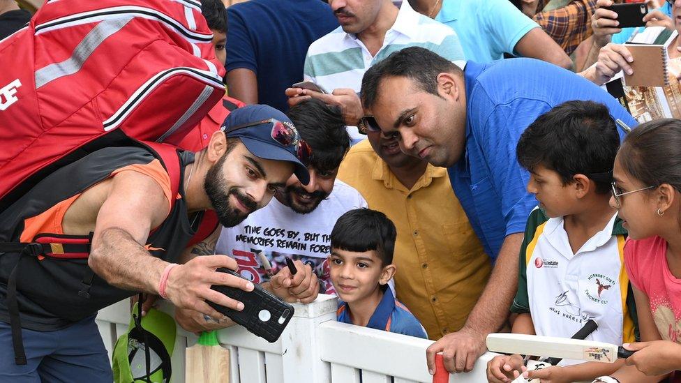 Virat Kohli taking a selfie with a young fan