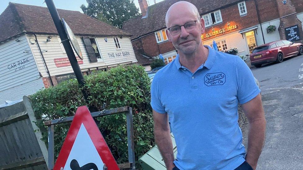 Jason Tharp, landlord of The George Inn pub in the background