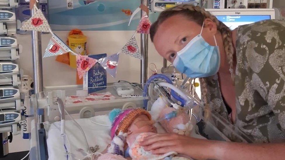 Charlotte Taylor stroking her baby daughter in a hospital crib