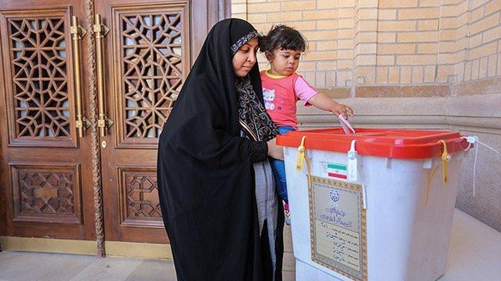 An Iranian woman holds a girl as she casts her vote during a second round of parliamentary elections, in Shiraz, Iran April 29, 2016