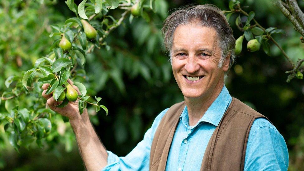 Phil Haughton smiling whilst holding an apple tree