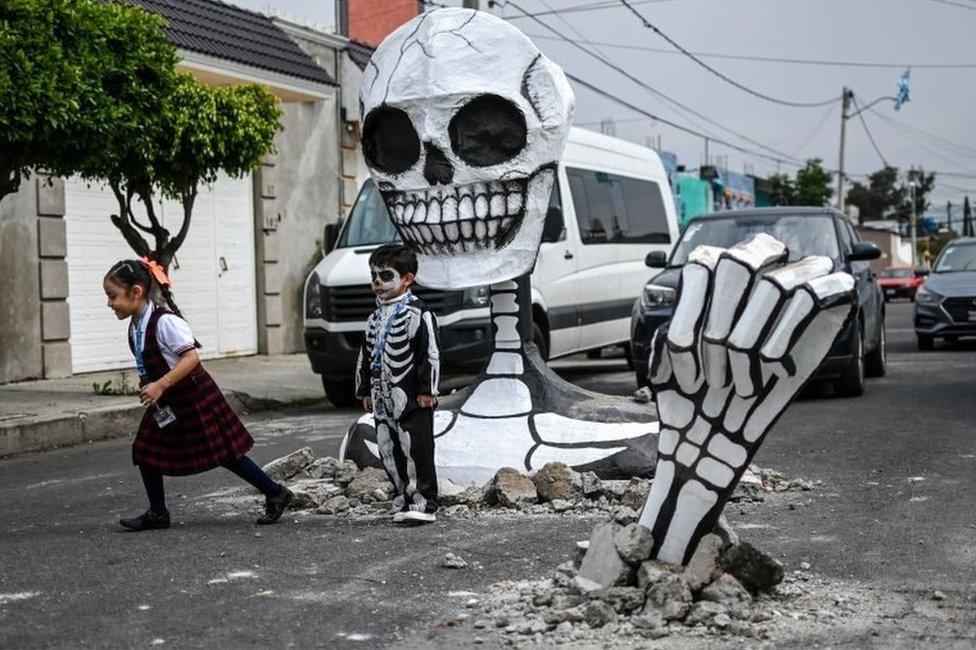 Children pose next to the cardboard skeleton