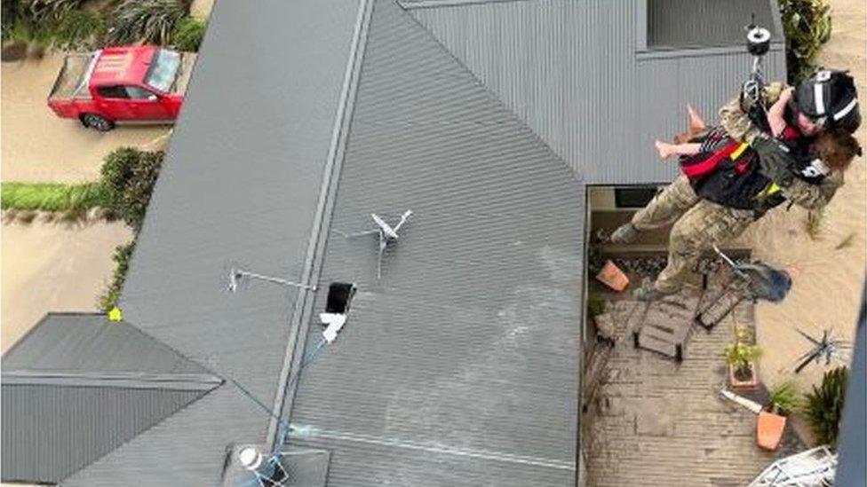 A helicopter and crew rescue people from rooftops