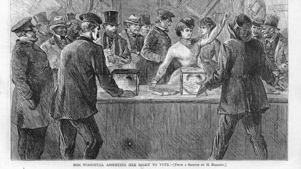 Black and white print illustrating Victoria Woodhull, the first woman candidate for President, with her arm raised, after breaking into a polling station and demanding to be allowed to vote, titled "Mrs Woodhull Asserting her Right to Vote, " illustrated by H Balling for the American market, 1871