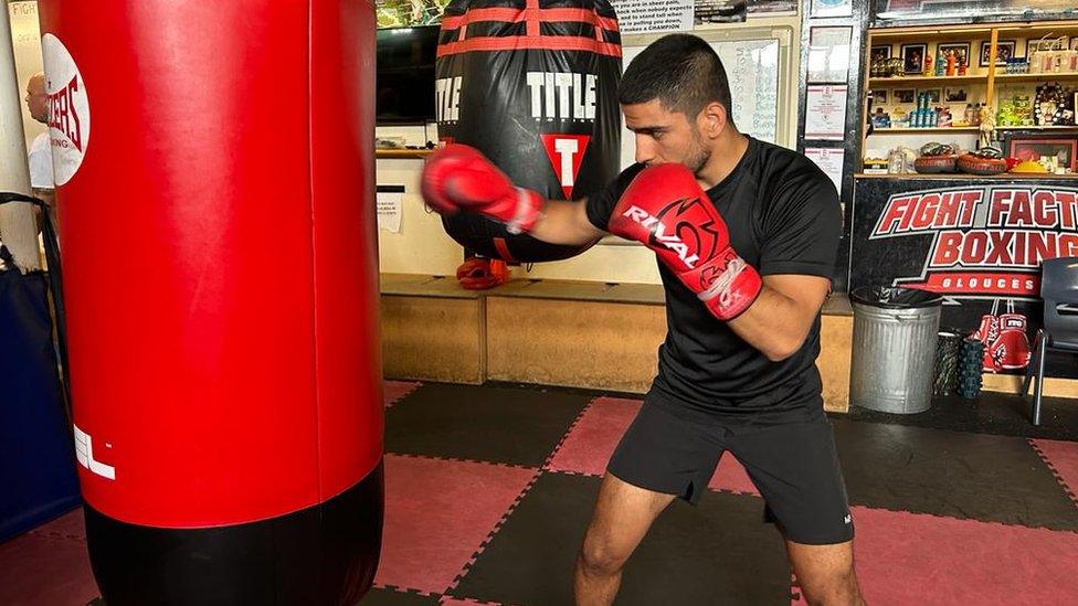 Shabir Haidary in a boxing pose next to a punching bag