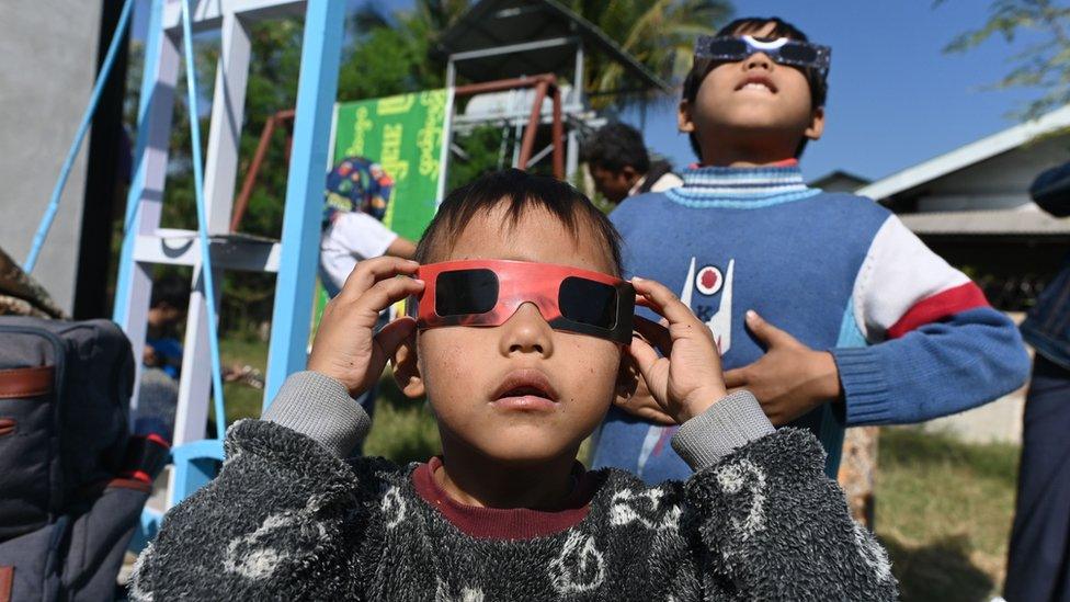 Children uses eclipse glasses to watch a rare "ring of fire" solar eclipse in Wan Twin in central Myanmar on December 26, 2019