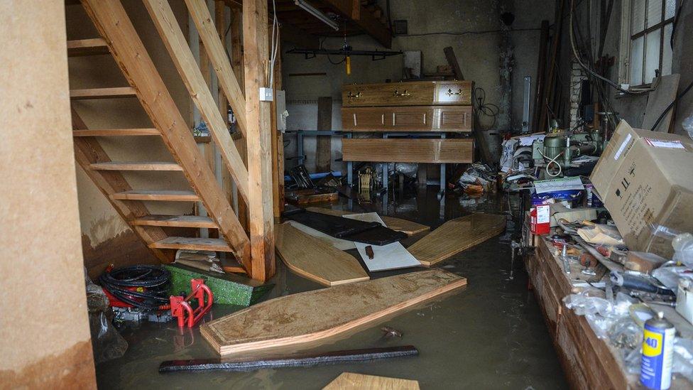 Coffins float around inside a flooded funeral parlour in Fishlake