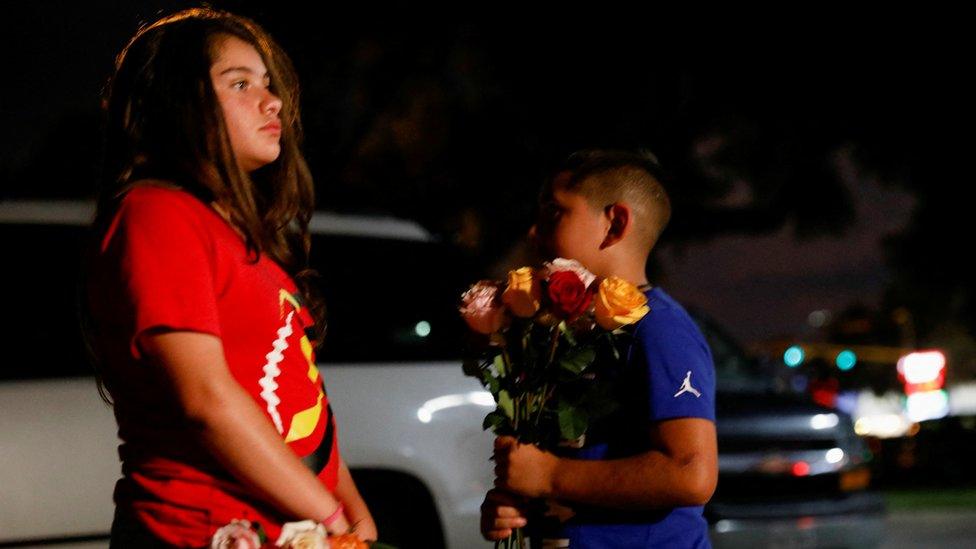 A boy holds flowers outside the school in Uvalde