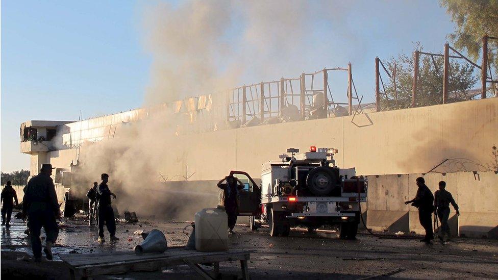 Afghan security forces try to douse a fire after a suicide car bomb blast attacked a military convoy in Lashkar Gah