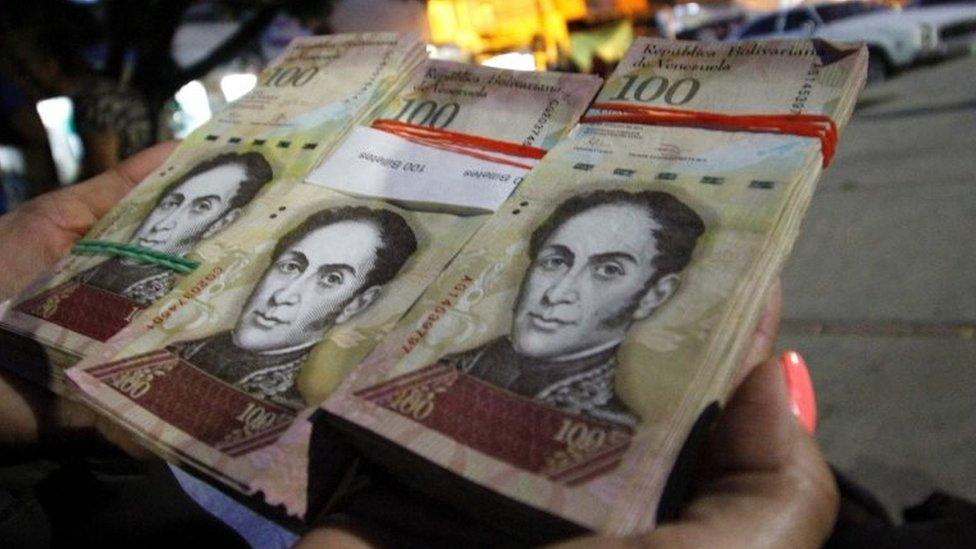 A woman shows wads of 100-bolivar-bills to change in La Parada, municipality of Villa del Rosario, Norte de Santander department, Colombia, in the border with Venezuela, on December 11, 2016.