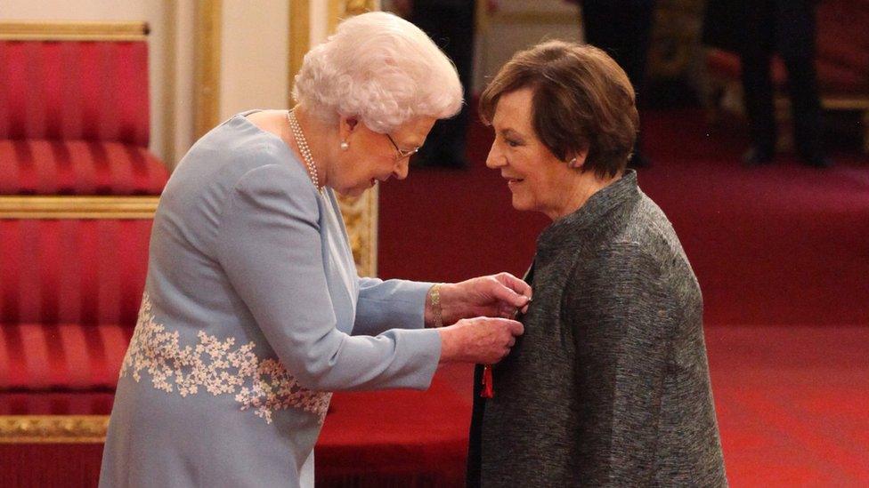 The Queen pinning the award to Delia Smith's coat