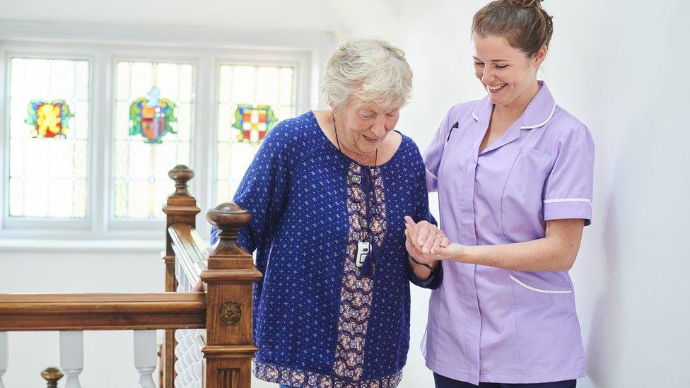 Female Care Worker helps elderly woman to climb stair