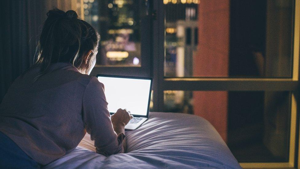 woman on laptop at night by window