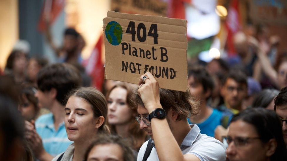 Young people protesting, with climate placard that reads "404 planet b not found"