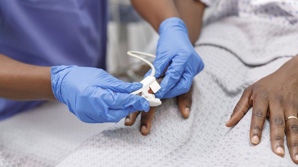 A nurse putting a heart rate monitor on a patient's forefinger