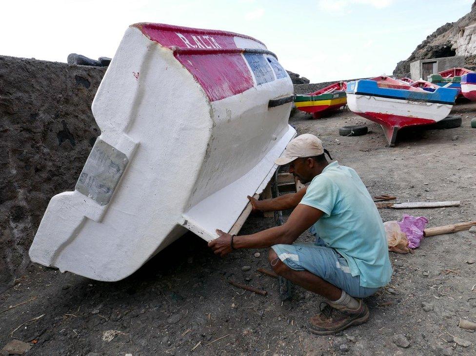 A man mends a boat on the island of Santo Antao.