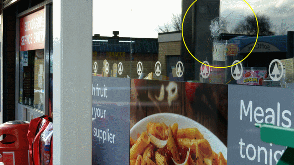 Bullet holes in the windows of the filling station