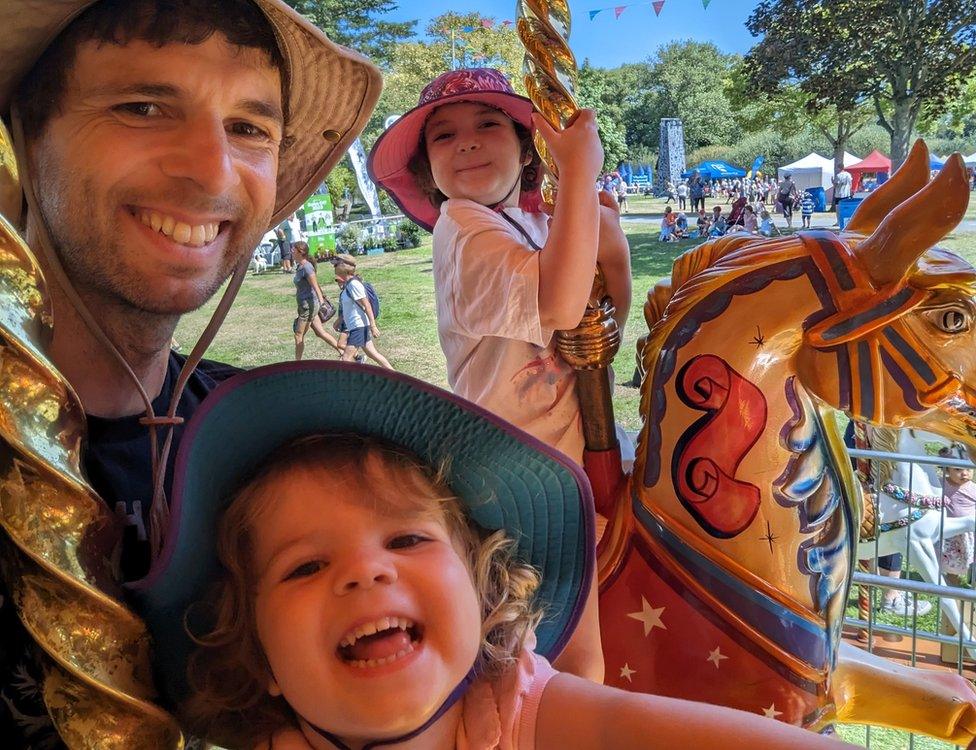 Man and two daughters riding a carousel